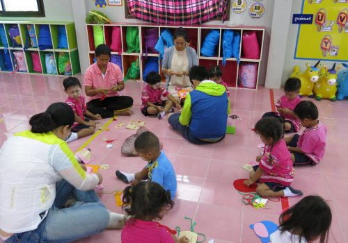 Participant teaching kids how to make handicraft